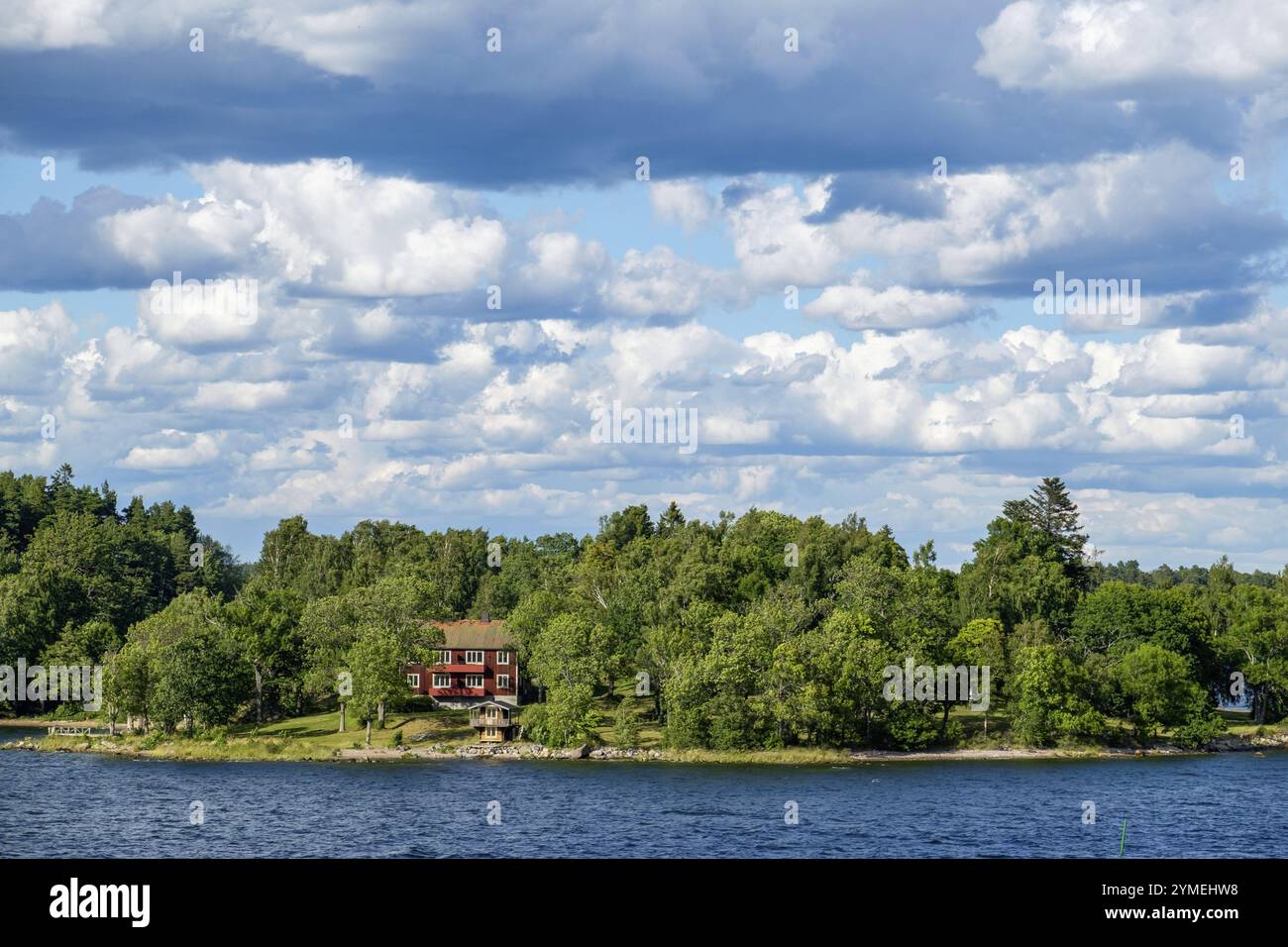 Rotes Haus umgeben von Bäumen vor einem bewölkten Himmel, Archipel, stockholm, schweden Stockfoto