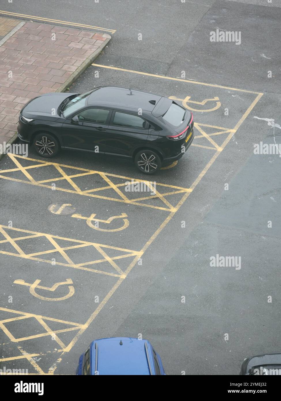 Behindertenparkplätze. Blick von oben auf ein Auto in einem ausgewiesenen Bereich des Parkplatzes, der für Menschen mit Behinderungen reserviert ist. Stockfoto