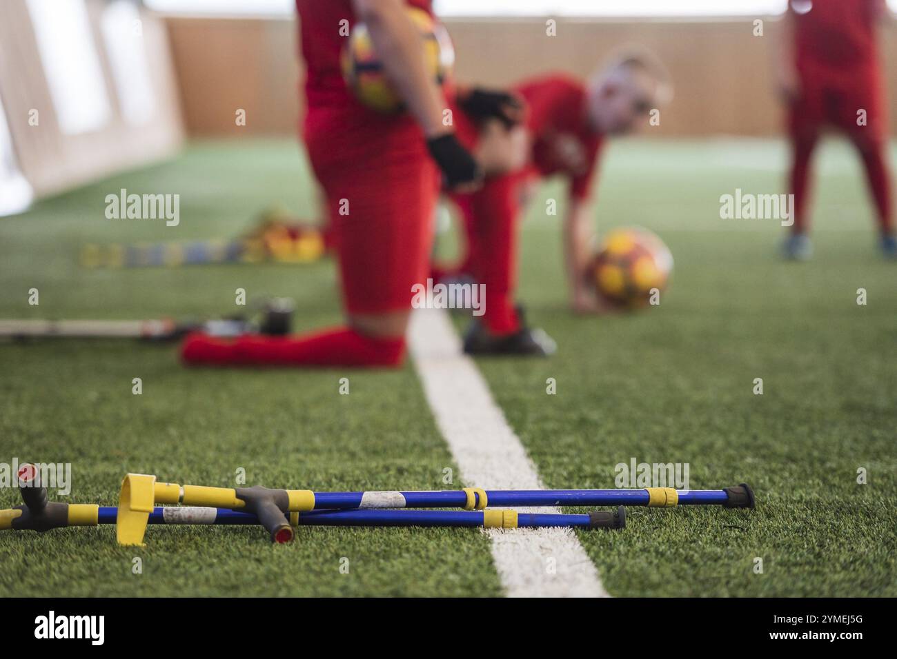 Krücken liegen auf dem Kunstrasen mit behinderten Fußballspielern im Hintergrund. Stockfoto