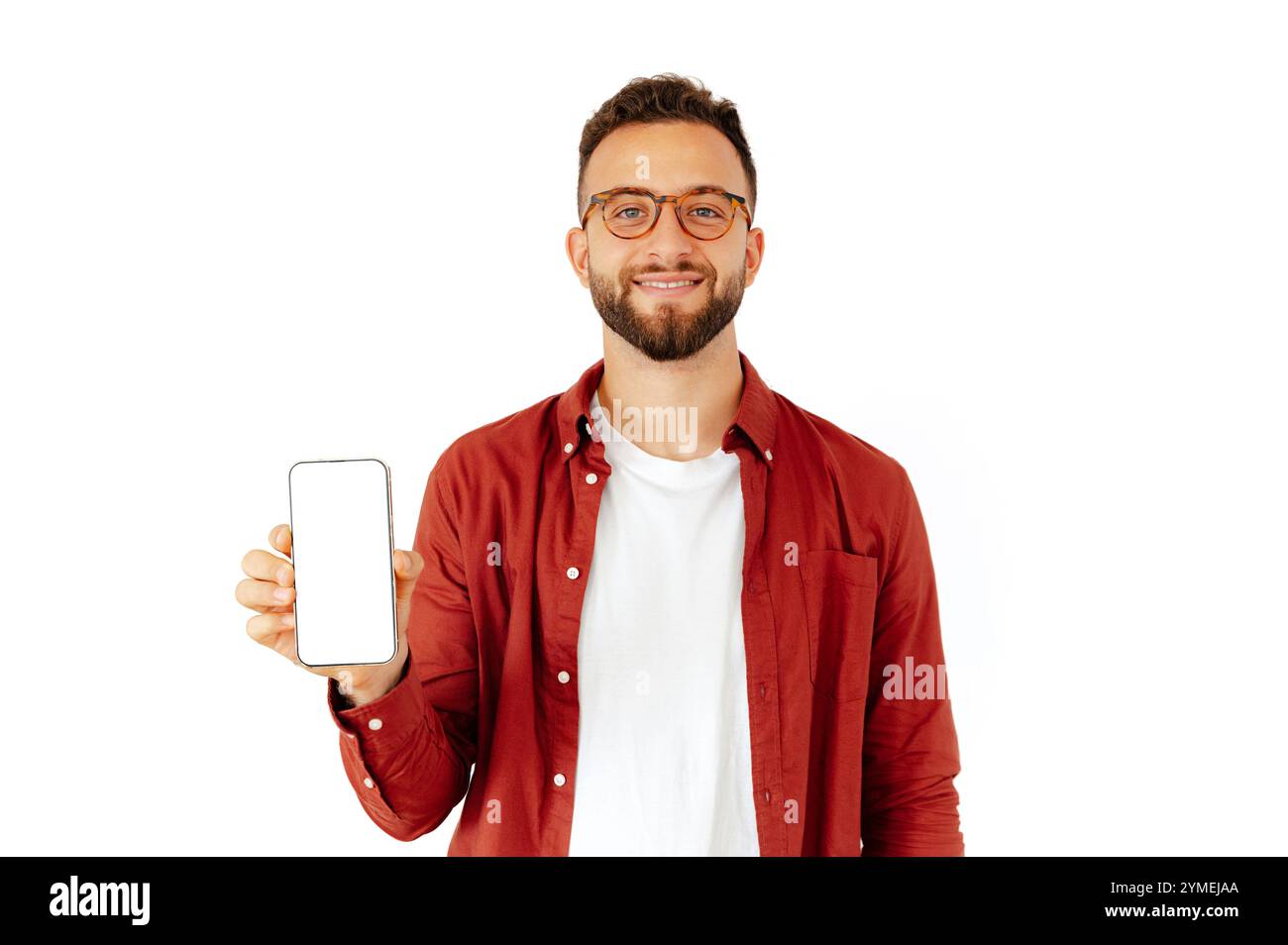 Positiver weißer oder arabischer junger Mann, der ein Smartphone in der Hand hält, einen leeren weißen Mock-up-Bildschirm für Werbung oder Präsentation präsentiert, auf isoliertem weißem Hintergrund steht, lächelt freundlich Stockfoto