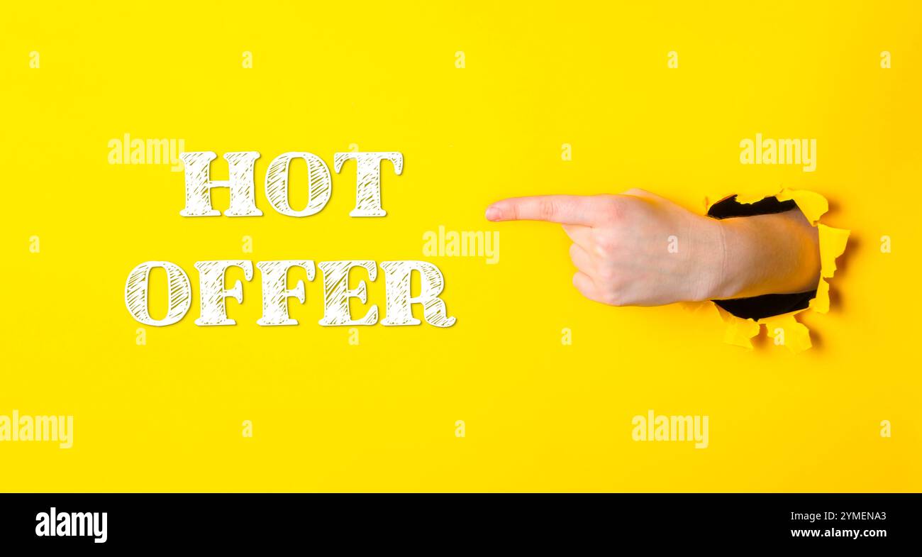 Hand, die auf das Wort HOT OFFER auf gelbem Hintergrund zeigt. Konzept der Dringlichkeit und Begeisterung, als ob das Angebot zeitlich begrenzt oder exklusiv ist Stockfoto