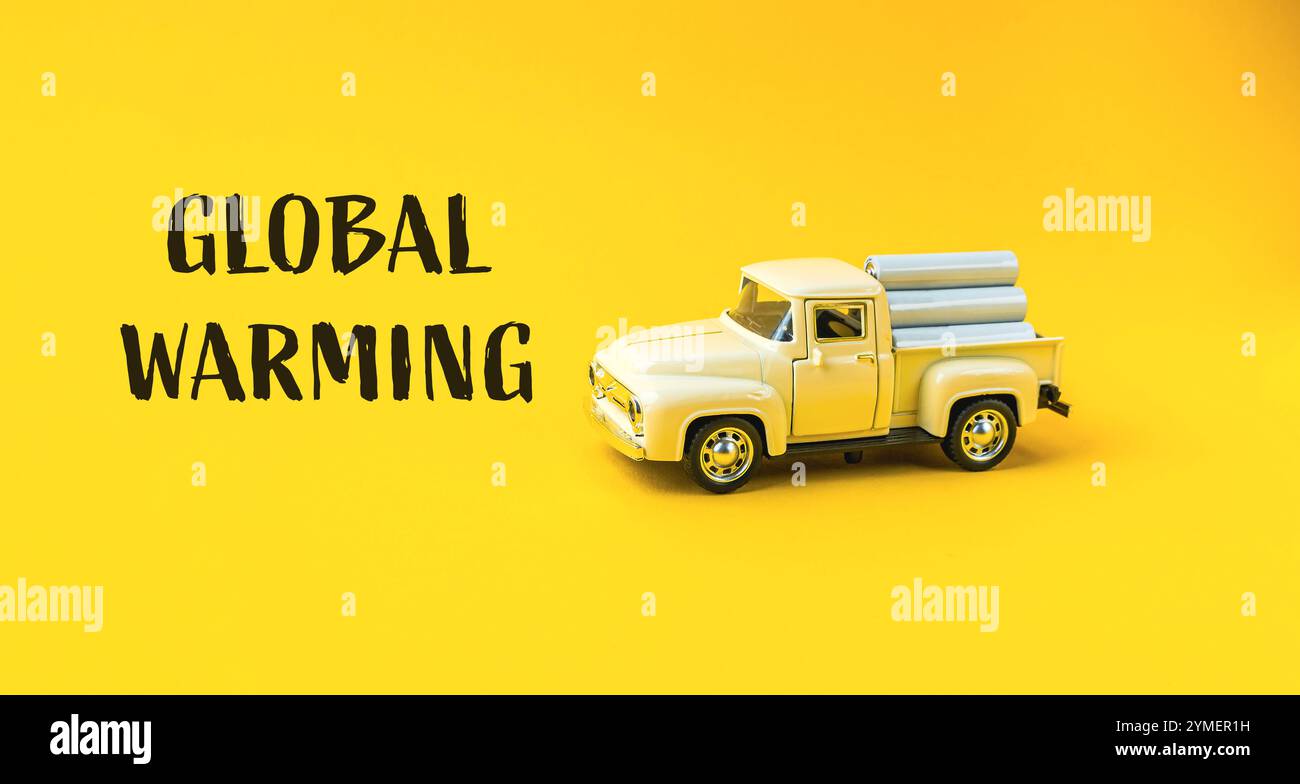 Der Spielzeugwagen ist auf gelbem Hintergrund mit der Aufschrift „Global Warming“ darunter. Der Lkw ist von einem Holzhaufen umgeben, der t darstellen könnte Stockfoto