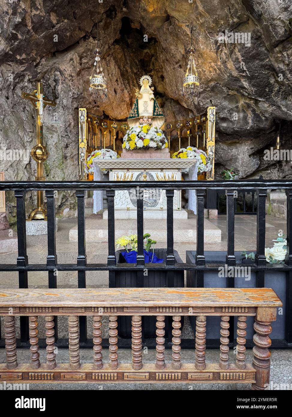 Statue von La Santina (oder unserer Lieben Frau von Covadonga) mit Gebetsbänken im Vordergrund in der Heiligen Höhle von Covadonga, Asturien, Spanien Stockfoto