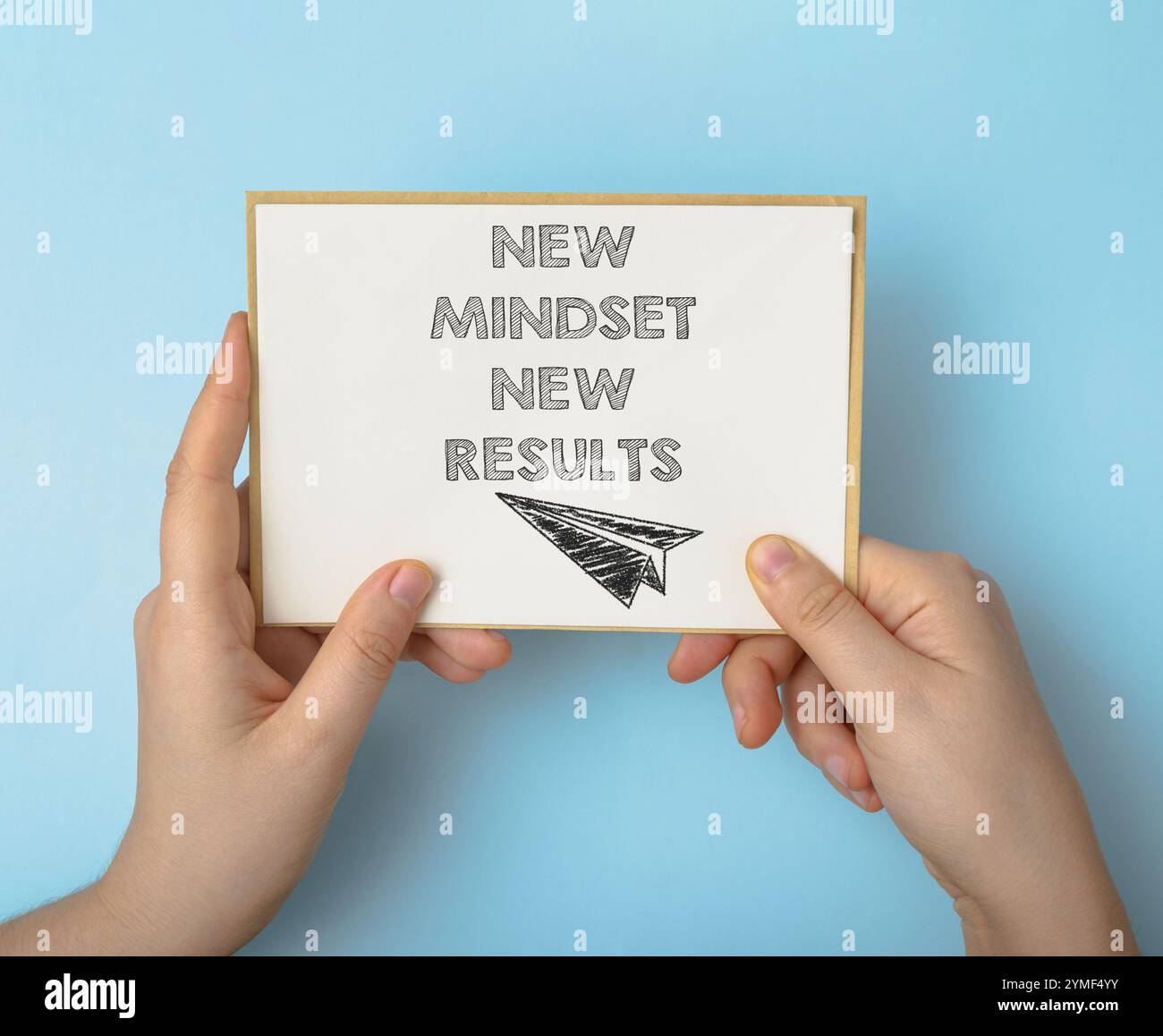 Die Person hält eine Karte mit der Aufschrift „neue Denkweise“, „neue Ergebnisse“. Die Karte soll die Person wahrscheinlich dazu inspirieren, eine neue Denkweise zu übernehmen Stockfoto
