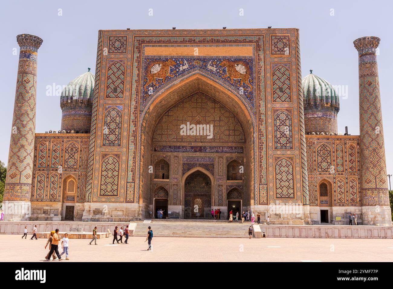 Besucher treffen sich auf dem berühmten Registan-Platz von Samarkand, Usbekistan. Die historische Madrassah und die lebendige Atmosphäre spiegeln Jahrhunderte von Kultur und wider Stockfoto