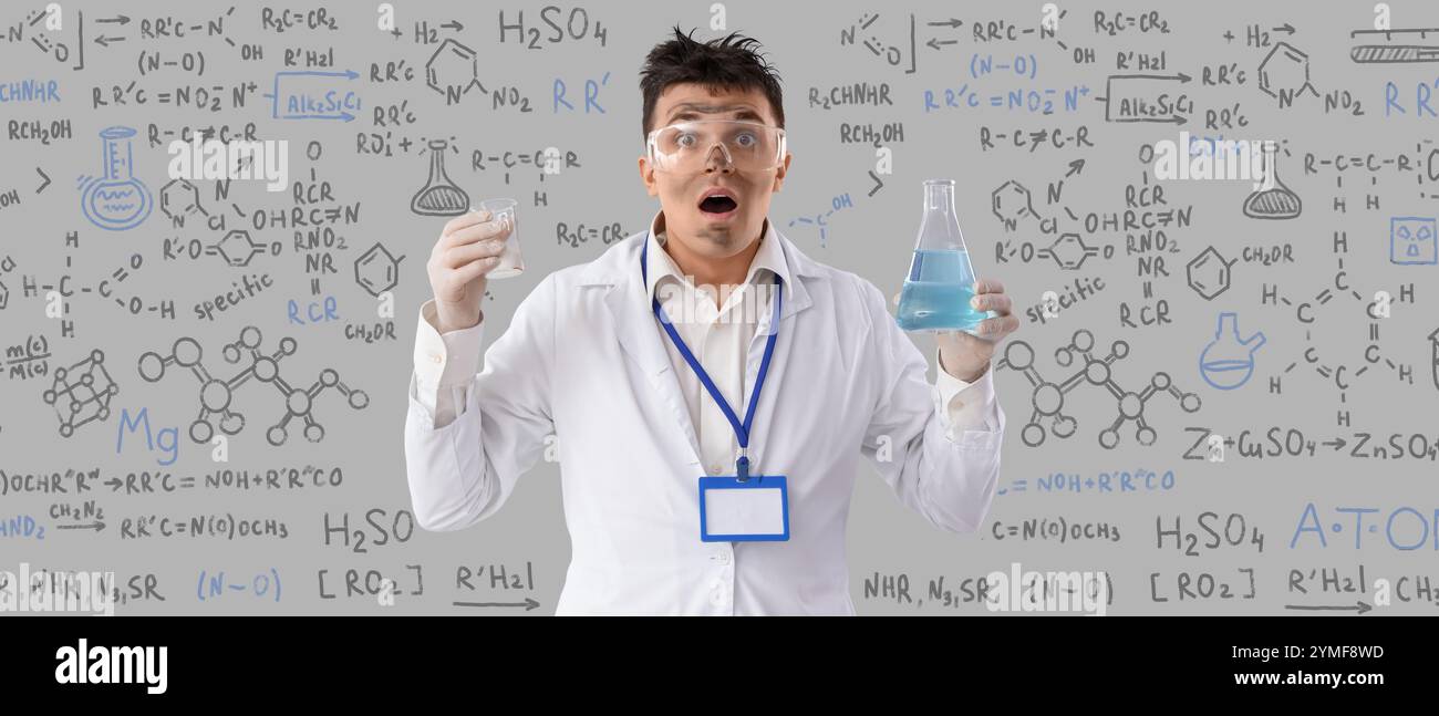 Schockierter männlicher Chemiker mit schmutzigem Gesicht als Folge einer Explosion auf grauem Hintergrund Stockfoto
