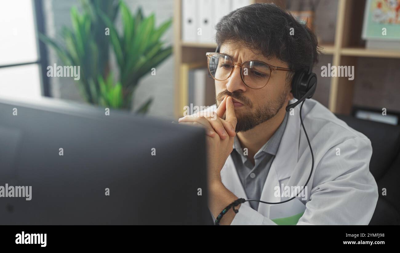 Ein nachdenklicher arabischer Mann mit Bart und Brille, der ein Headset und einen Labormantel in einer modernen Büroumgebung trägt, was auf eine medizinische Beratung hindeutet. Stockfoto