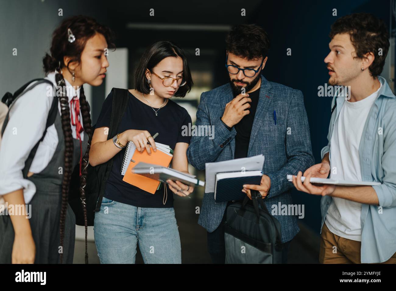 Schüler, die zwischen den Unterrichtseinheiten eine durchdachte Diskussion mit dem Professor führen Stockfoto