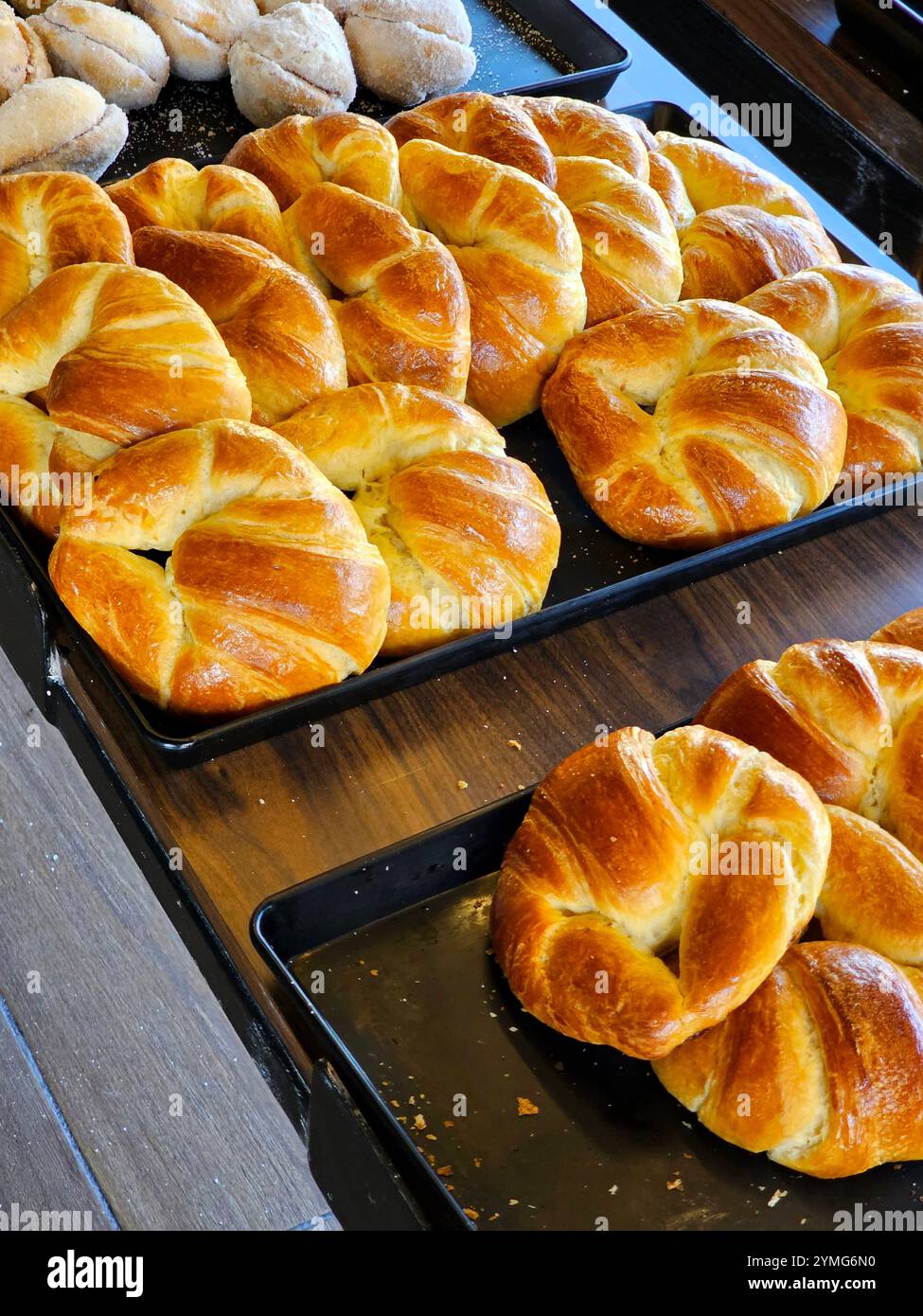 Tablett in der Bäckerei mit frischen Croissants, fettigem Blätterteigbrötchen, im Ofen gebacken, in Form einer Halbmond oder eines Horns Stockfoto