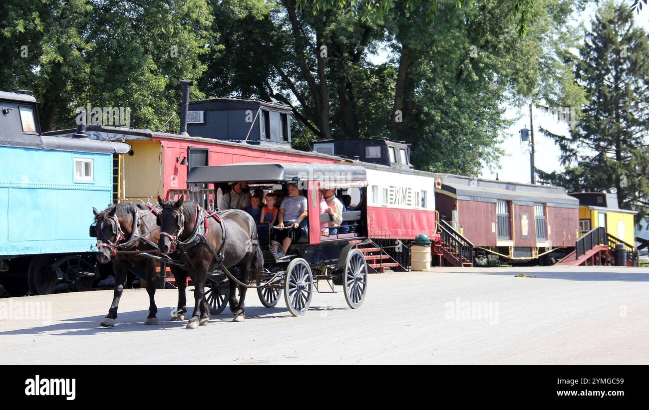 Ausflugswagen, gezeichnet von ein paar Pferden, bunte alte Kaboose im Hintergrund, im Amischen Land bei Strasburg, im Lancaster County, PA Stockfoto