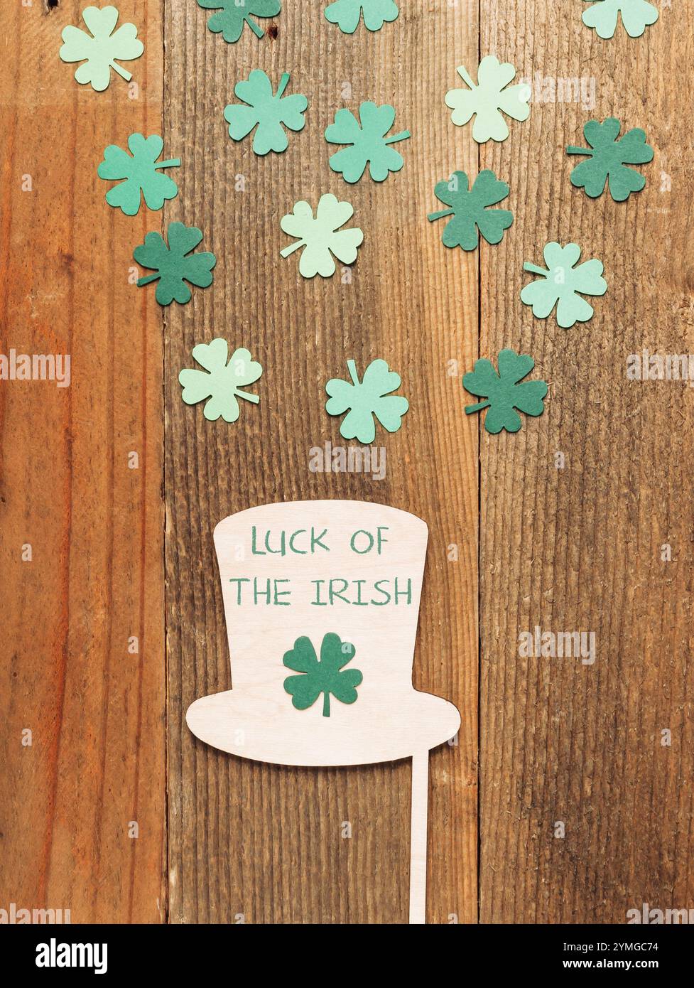 Grüner Schamrock-Hut mit den Worten "Lucky of the Iren" darauf. Der Hut ist von vielen grünen Schamrock umgeben Stockfoto
