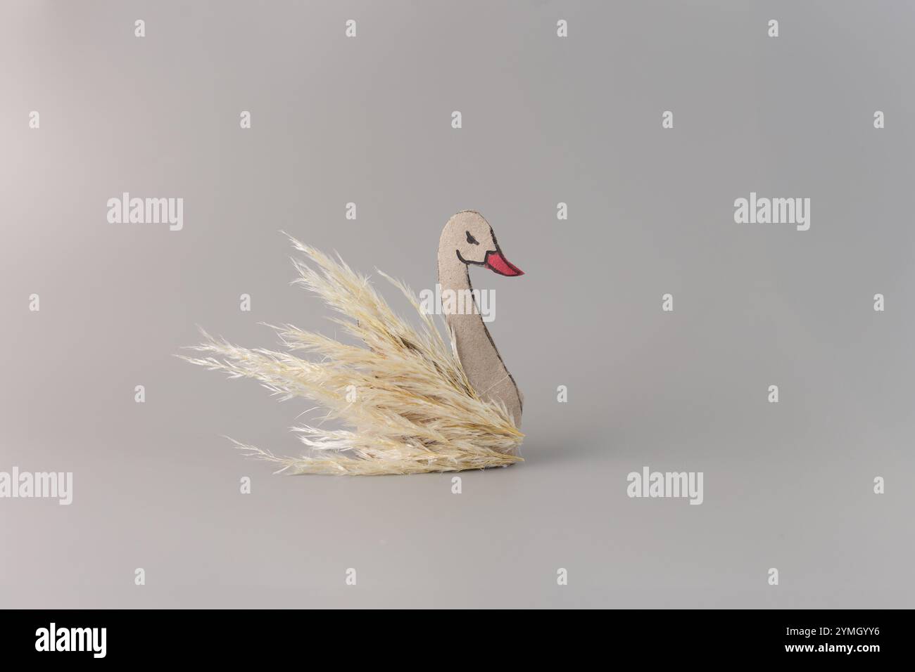 DIY-Schwan-Figur aus Pappe und Pampas-Gras auf grauem Hintergrund, umweltfreundliches Dekorationsprojekt für kreatives Hobby und Upcycling-Design-Inspir Stockfoto