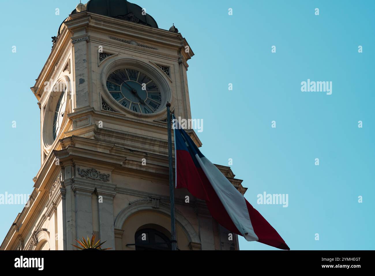 Blick auf das Museum mit seinem Uhrenturm, neben der schwenkenden chilenischen Flagge, mit einem klaren Himmel an einem sonnigen Tag Stockfoto
