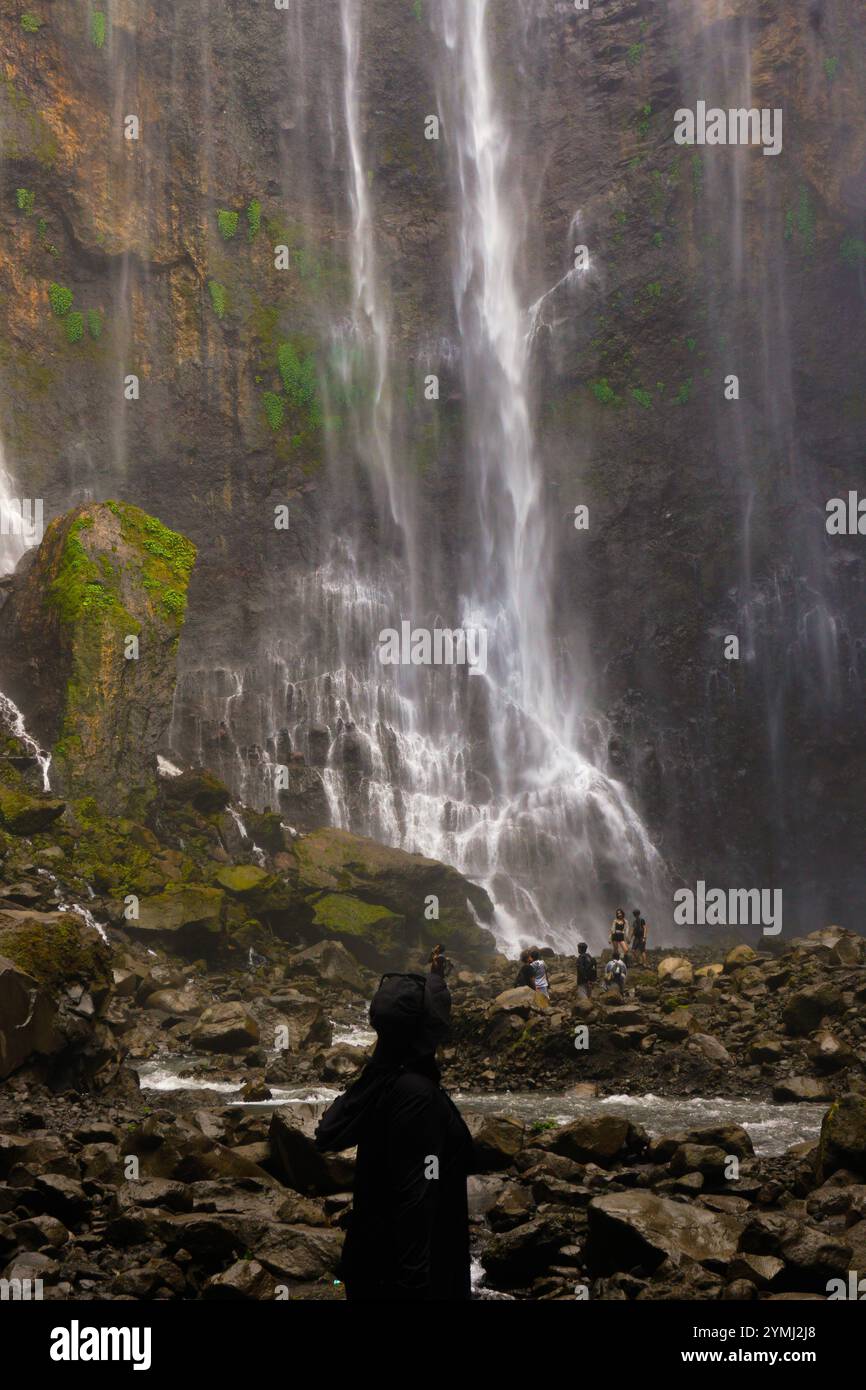 Eine weibliche Touristen, die die atemberaubende Aussicht auf den Tumpak Sewu Wasserfall in Indonesien genießt Stockfoto