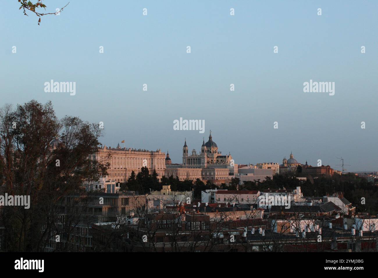 Blick auf Madrids Königspalast und die Kathedrale von Almudena bei Sonnenuntergang mit den Dächern der Stadt im Vordergrund, die Spaniens historischen Charme zum Ausdruck bringen. Stockfoto