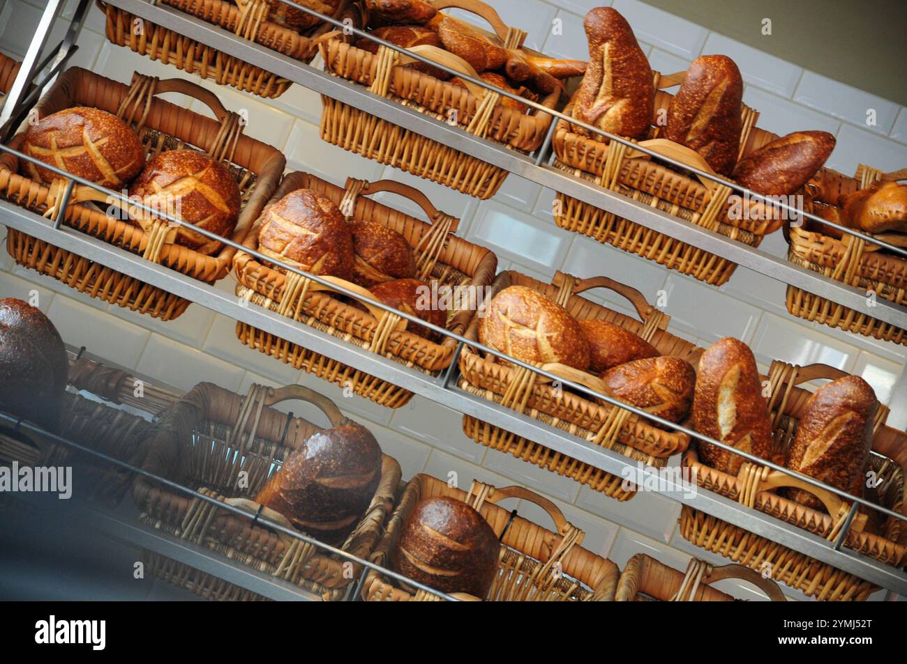 Frisch gebackenes Brot in Korbkörben auf rustikalen Bäckereiregalen Stockfoto