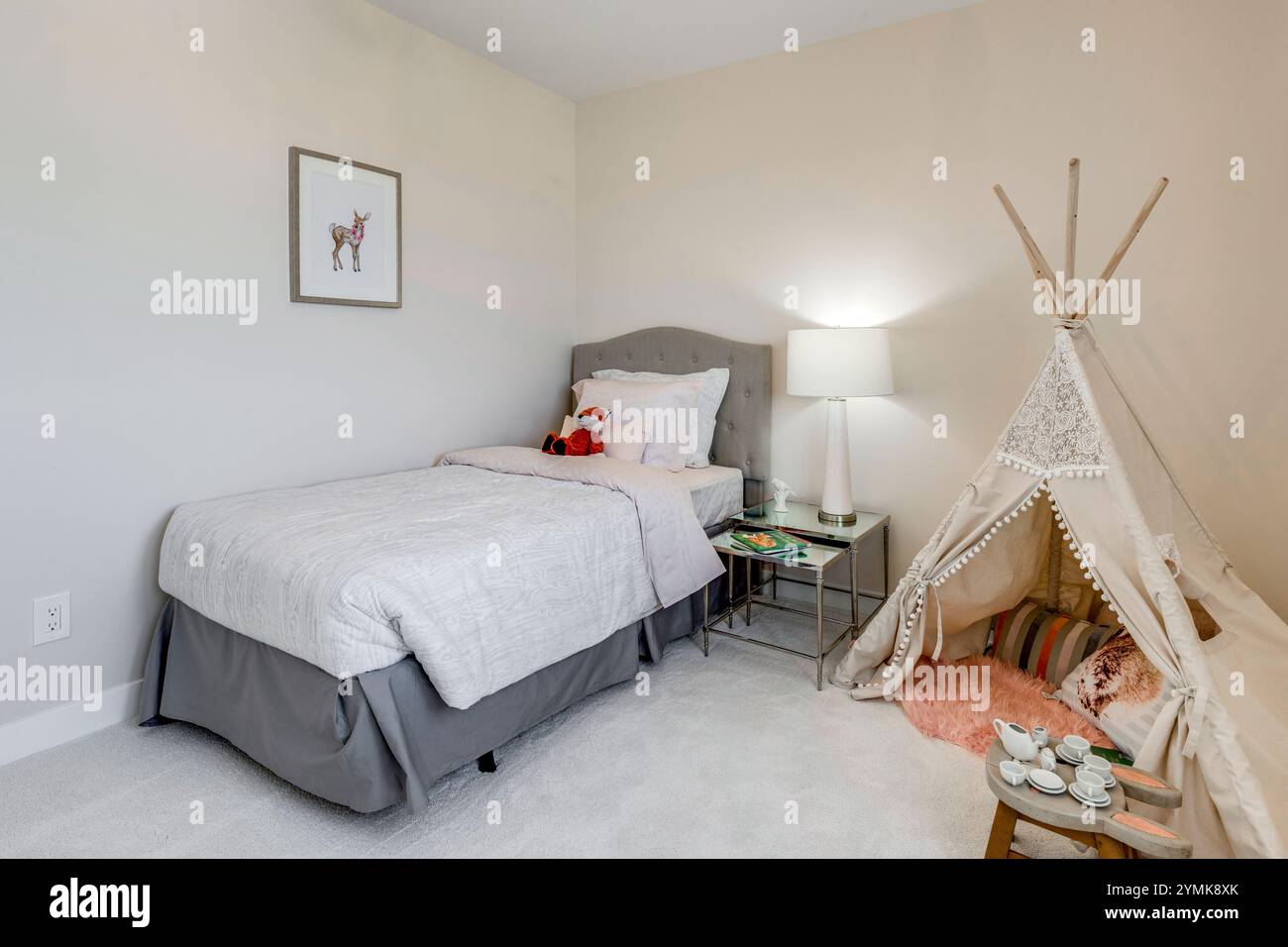 Ein kleines Schlafzimmer mit einem weißen Bett, einem weißen Nachttisch und einem weißen Zelt. Das Zimmer ist mit einem weißen Thema dekoriert und hat einen gemütlichen und einladenden geldautomaten Stockfoto