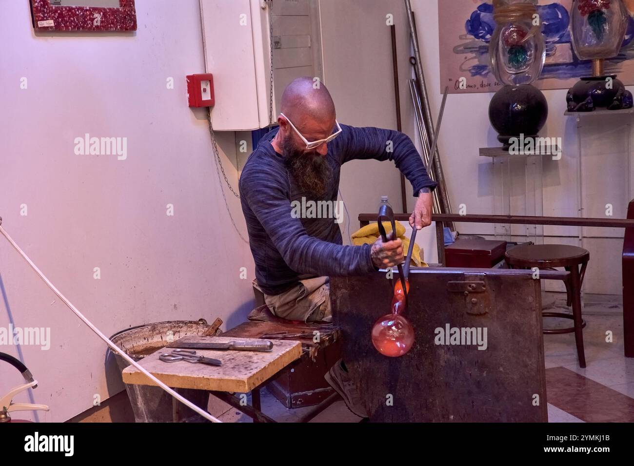 Venedig, Italien; 17. Oktober 2024: Ein schwieriger Prozess der Herstellung einer Murano-Glasfigur in einer historischen venezianischen Werkstatt. Der geschickte Handwerker formt sorgfältig Stockfoto