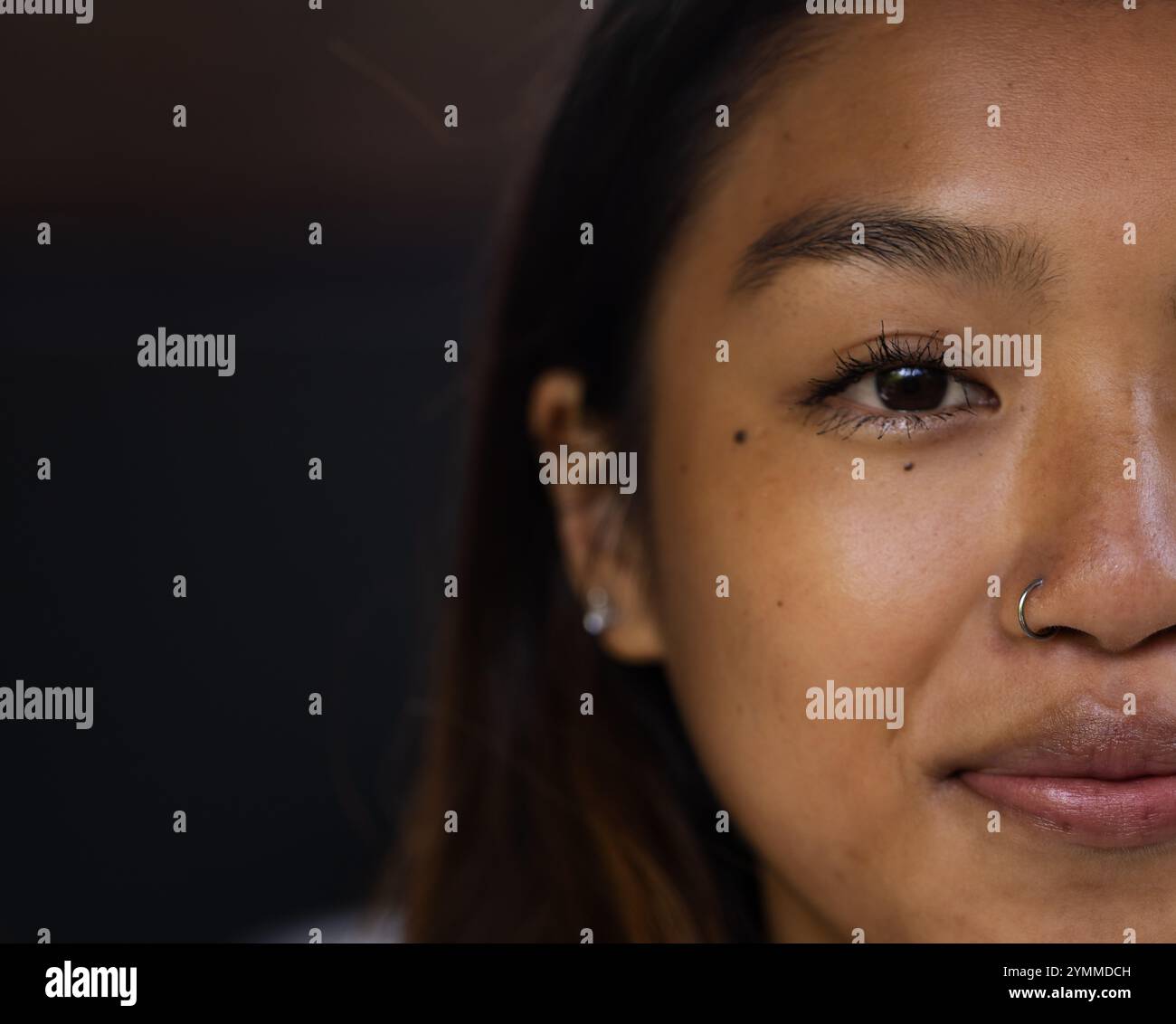 Nahaufnahme einer asiatischen Teenagerin, die mit Nasenring und Ohrringen lächelt, Kopierraum, zu Hause. Mode, Stil, Schmuck, Porträt, Ausdruck, Zubehör Stockfoto