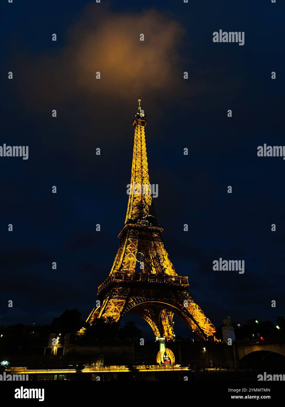 Paris, Frankreich - 19. Juni 2024: Der Eiffelturm steht majestätisch beleuchtet vor einem dunklen Nachthimmel, in Verbindung mit den glühenden Wolken darüber. Stockfoto