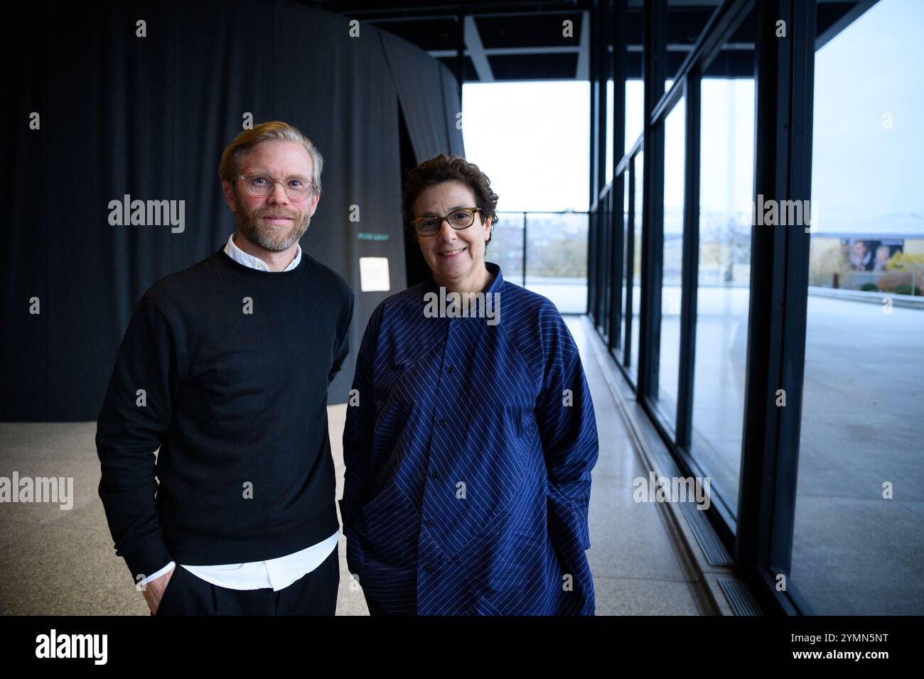 Berlin, Deutschland. November 2024. Fredrik Liew (l), Chefkurator des Moderna Museums in Stockholm und Kurator der Ausstellung, und Ausstellungsarchitektin Hala Wardé stehen vor einem der verdunkelten zeltartigen Räume der Neuen Nationalgalerie, wo Fotos von Nan Goldin als Diashow gezeigt werden. Die Retrospektive „This will Not End Well“ in der Neuen Nationalgalerie (23.11.2024 - 06.04.2025) ist der erste umfassende Einblick in das fotografische Werk des amerikanischen Künstlers Nan Goldin von 1980 bis heute. Quelle: Bernd von Jutrczenka/dpa/Alamy Live News Stockfoto