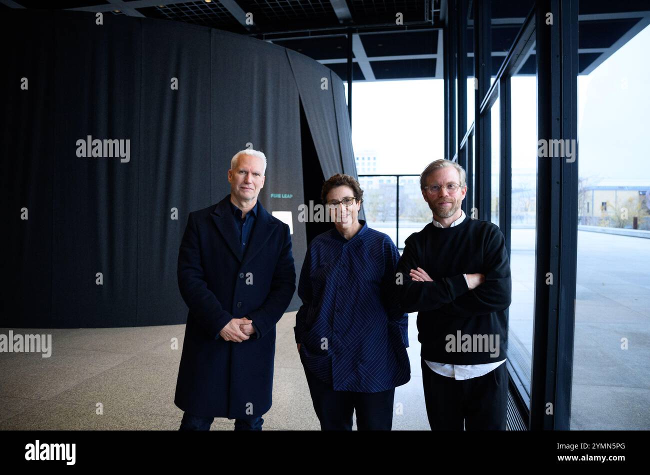 PRODUKTION - 21. November 2024, Berlin: Klaus Biesenbach (l-r), Direktor der Neuen Nationalgalerie, Ausstellungsarchitektin Hala Wardé und Fredrik Liew, Chefkurator des Moderna Museets in Stockholm und Kurator der Ausstellung, stehen vor einem der verdunkelten zeltartigen Räume der Neuen Nationalgalerie, in denen Fotos von Nan Goldin als Diaschau gezeigt werden. Die Retrospektive „This will Not End Well“ in der Neuen Nationalgalerie (23.11.2024 - 06.04.2025) ist der erste umfassende Einblick in das fotografische Werk des amerikanischen Künstlers Nan Goldin von 1980 bis heute Stockfoto