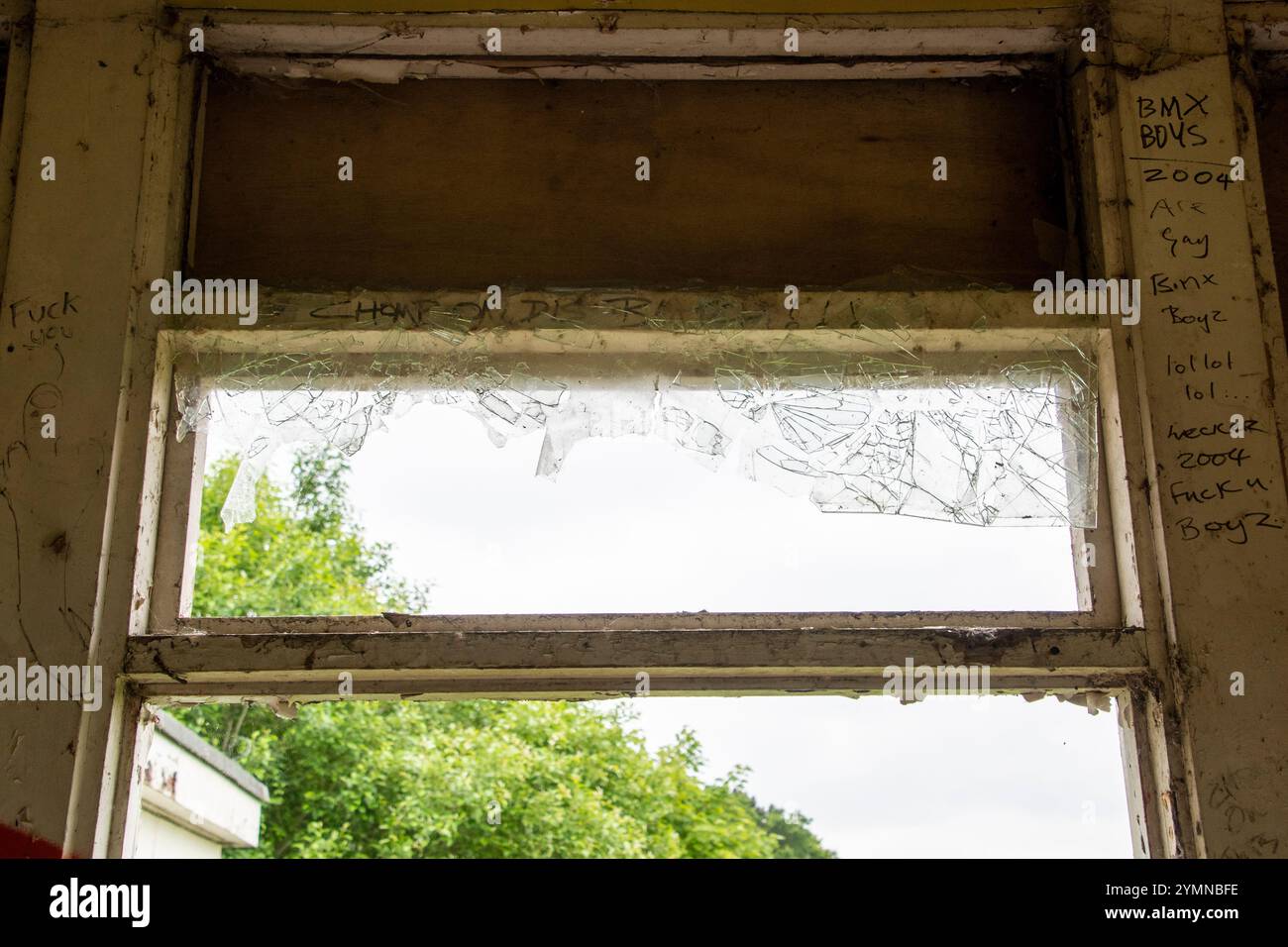 Yorkshire, Großbritannien: 31. Mai 2024 – Eine Fensterscheibe, gebrochen und mit Graffiti bedeckt, in einem verlassenen Gebäude Stockfoto