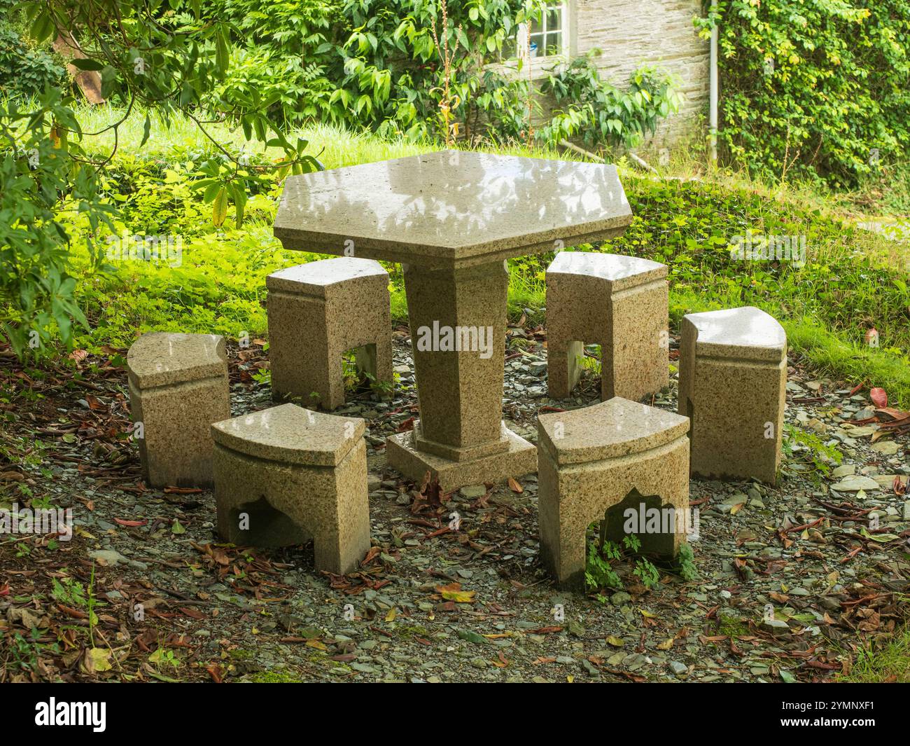 Sechseckiger Steintisch und Sitzplätze an einem schattigen Platz im Garden House, Buckland Monachorum, Devon, Großbritannien Stockfoto