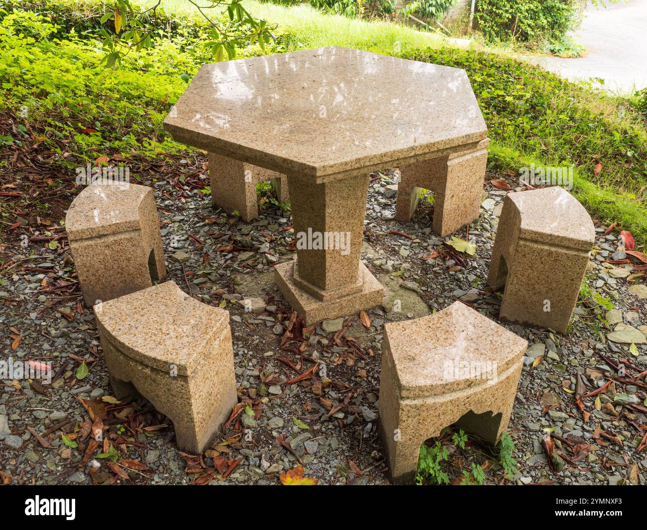 Sechseckiger Steintisch und Sitzplätze an einem schattigen Platz im Garden House, Buckland Monachorum, Devon, Großbritannien Stockfoto