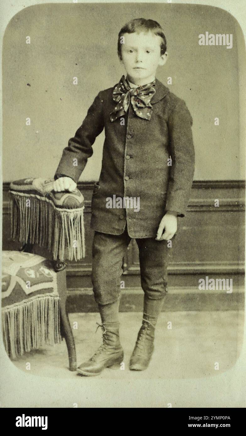 Ein Foto eines klug gekleideten Jungen, der sich auf einen Stuhl lehnte, um die 1880er Jahre Von einer Karte de Visite des Fotografen Laporte aus der Rue de Chalons, Mourmelon le Grand, Frankreich. Das Camp de Mourmelon wurde 1857 eröffnet und Laporte beschrieb sein Atelier als Grande Photographie de L’Armee. Stockfoto