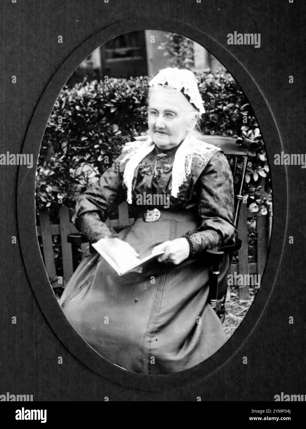 Foto von Mary Ann Jewell (1836–1923, geb. Luxton), einer älteren Dame, die möglicherweise in Kent, England lebt. Sie heiratete 1857 in Bideford, Devon. Die Abbildung zeigt, dass Sie im Freien sitzen, mit einem Schnürhut, einer Brille, einer Schnalle und einem Buch lesen können. Ursprünglich fotografiert von E. Dorrill aus Canterbury Street, Gillingham, Kent. Stockfoto