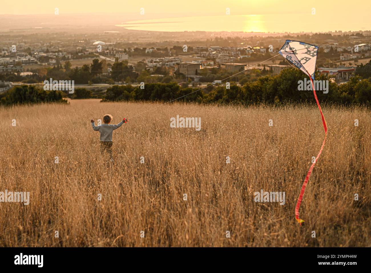 Junge auf dem Feld bei Sonnenuntergang mit Kite Stockfoto