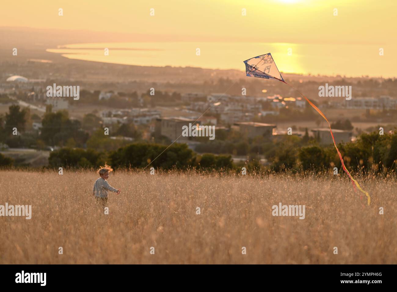 Junge auf dem Feld bei Sonnenuntergang mit Kite Stockfoto