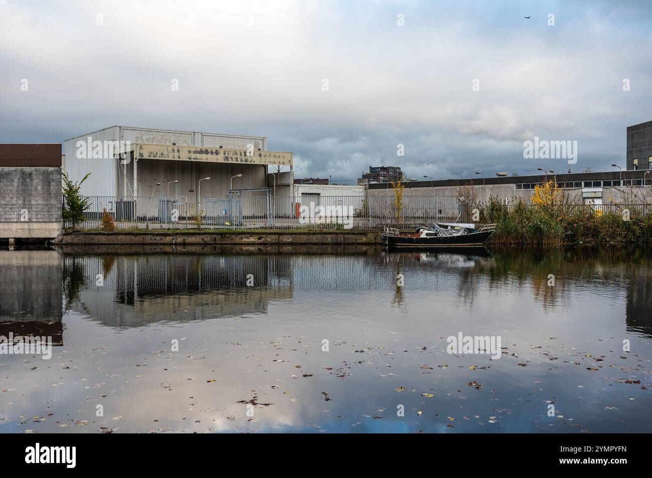 Häuser, verlassene Industrie und Boote reflektieren im westlichen Marktkanal in Amsterdam, Niederlande, 15. November 2024 Stockfoto