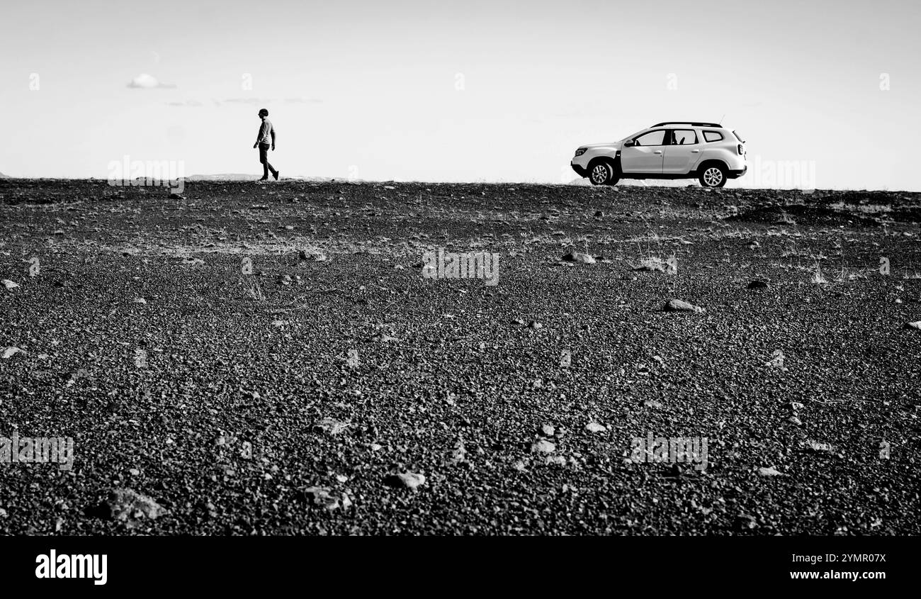 Ein Mann neben einem Auto auf einer verlassenen Straße Stockfoto