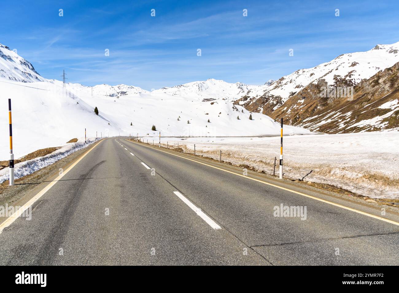 Verlassene Passstraße, die an einem sonnigen Tag von schneebedeckten Gipfeln abgerundet wird Stockfoto