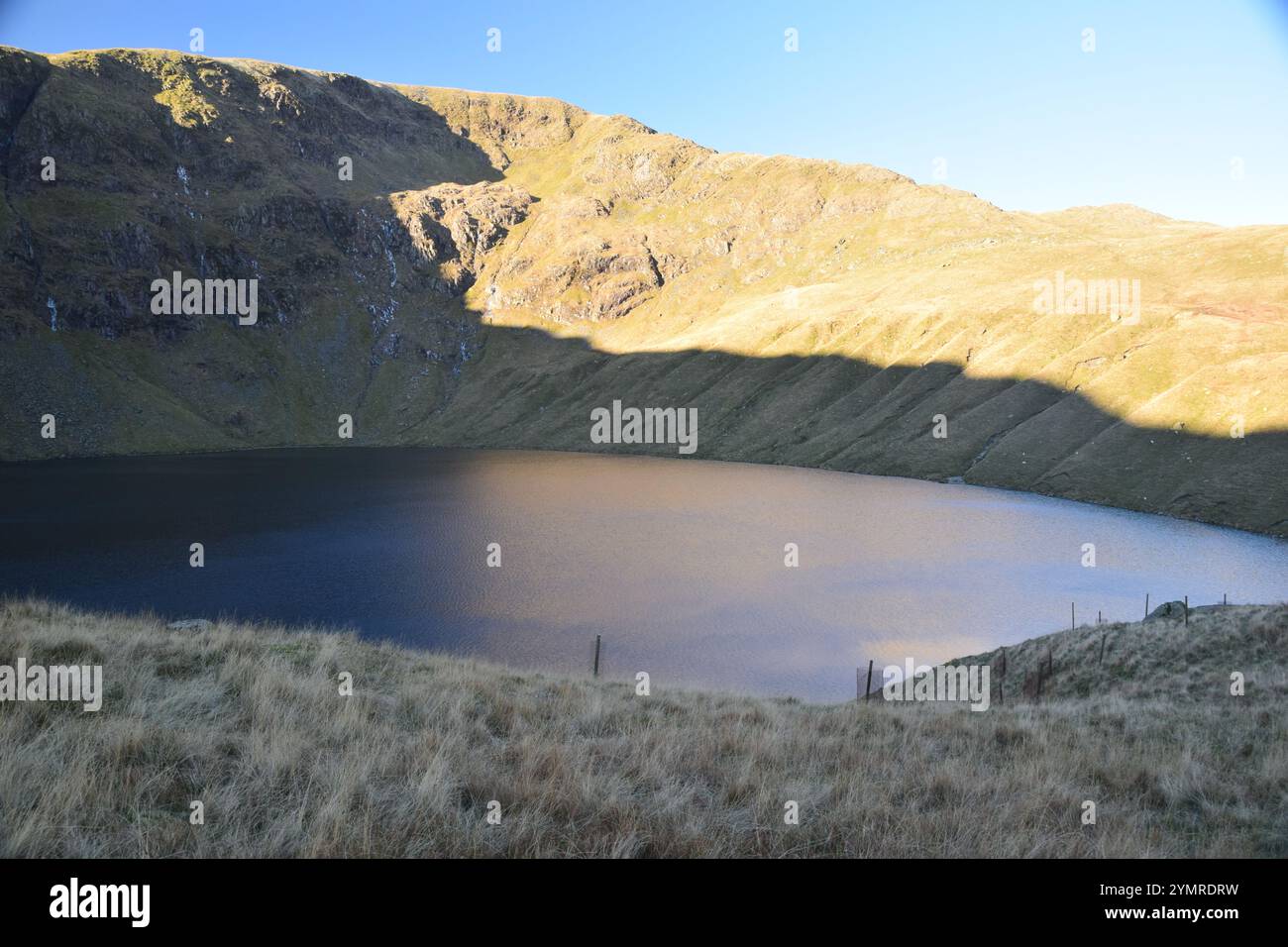 Sonnenlicht und Schatten an Blea Water und High Street Felswänden, English Lake District. Stockfoto