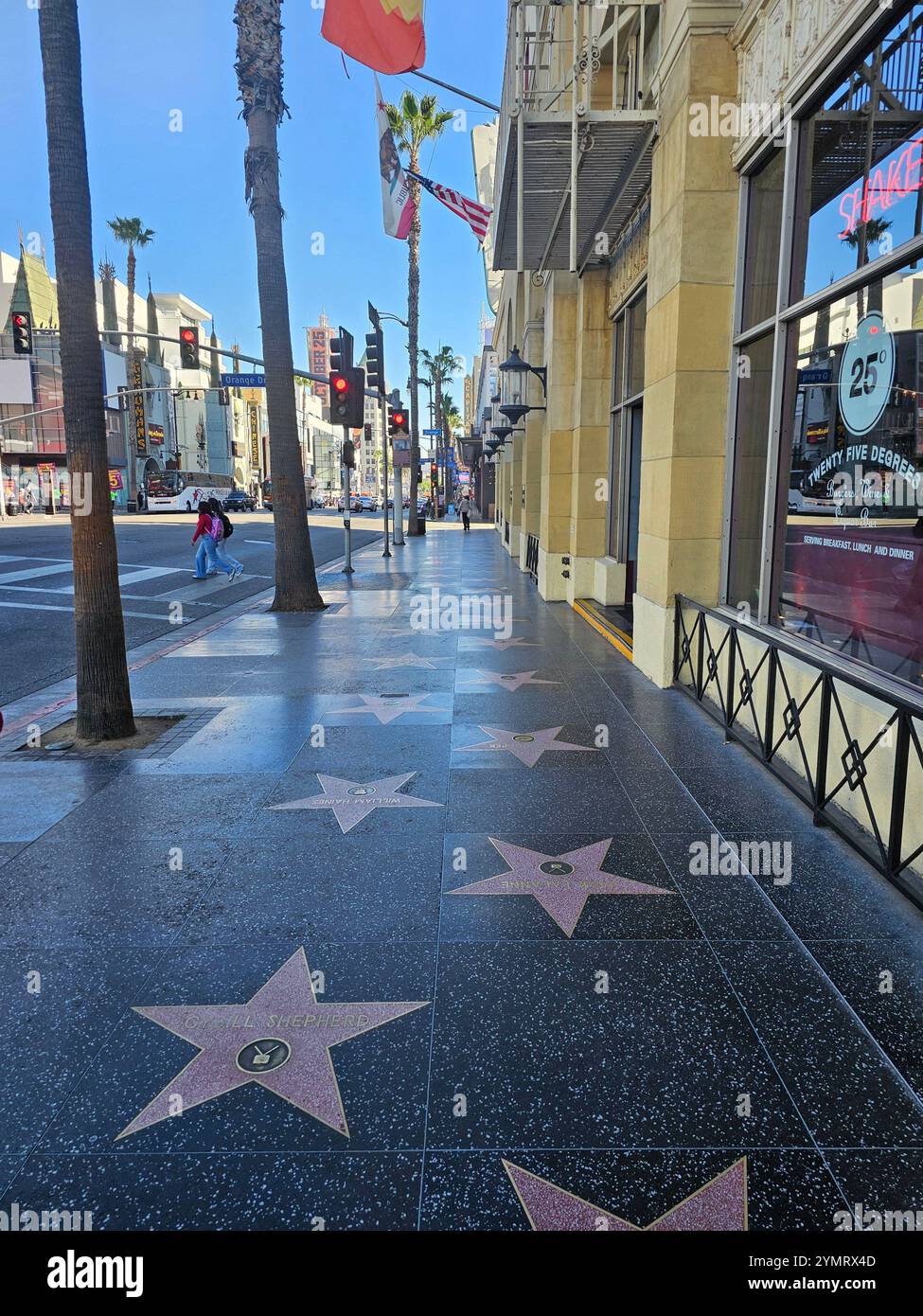 „Hollywood Walk of Fame an einem sonnigen Tag mit Touristen, Palmen und dem berühmten Orange Drive Straßenschild. Perfekt für Themen wie Tourismus und Kultur Stockfoto