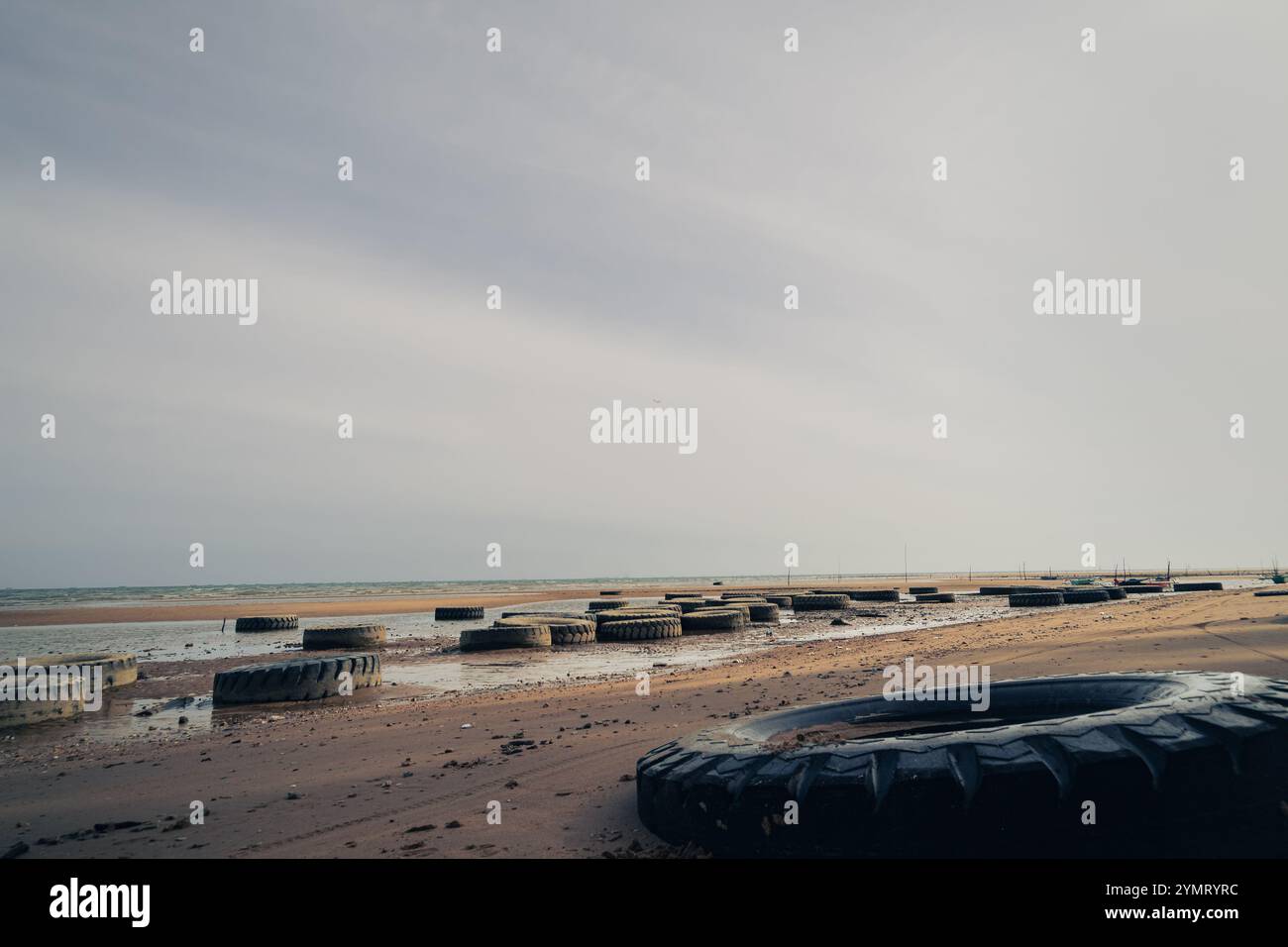 Wellenbrecher aus gebrauchten Reifen am Strand Stockfoto