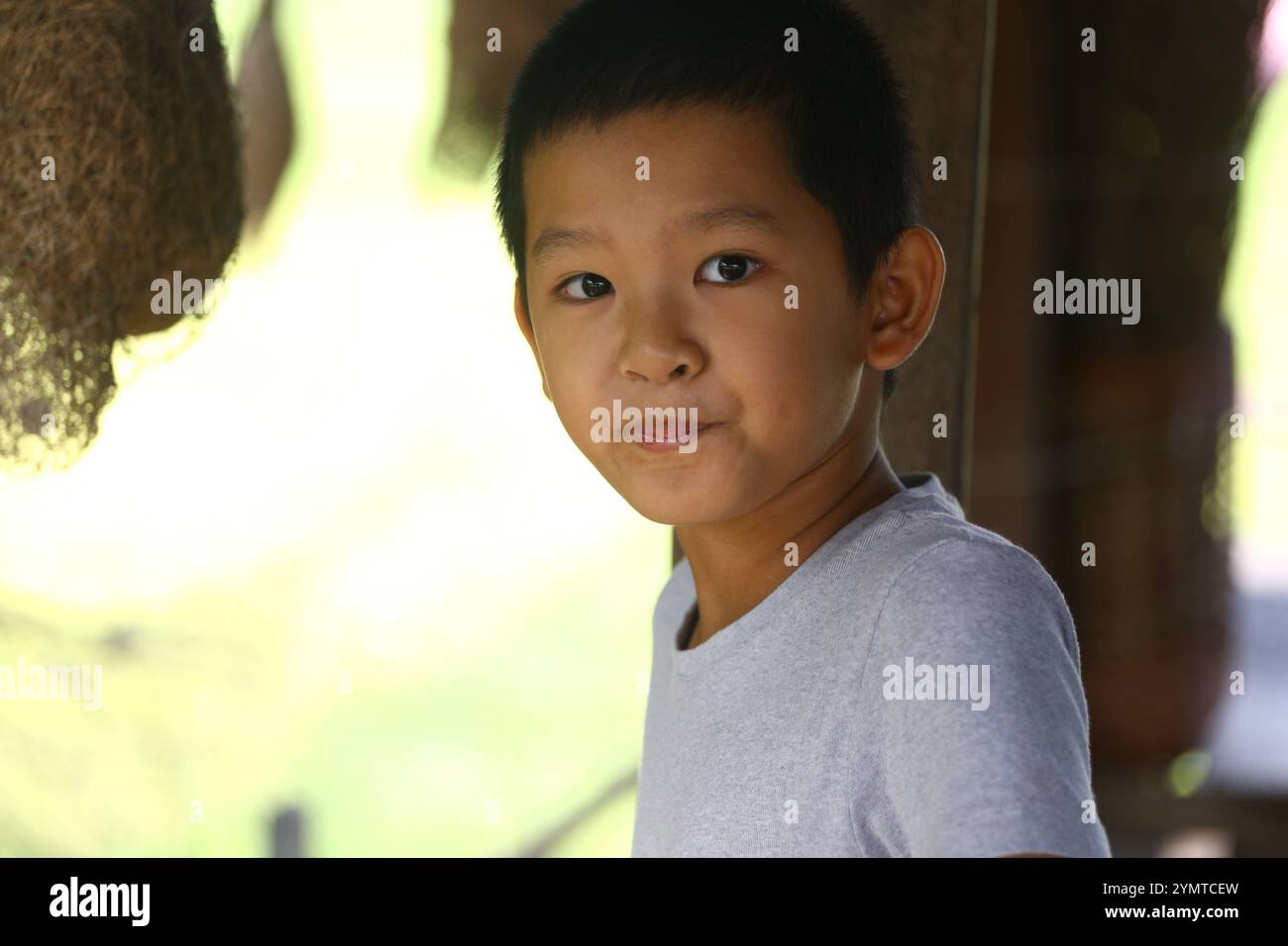 Ein kleiner Junge lächelt verspielt im Freien und zeigt Unschuld und Freude in einer natürlichen Umgebung, mit sanfter Beleuchtung und einem lebendigen Hintergrund. Stockfoto