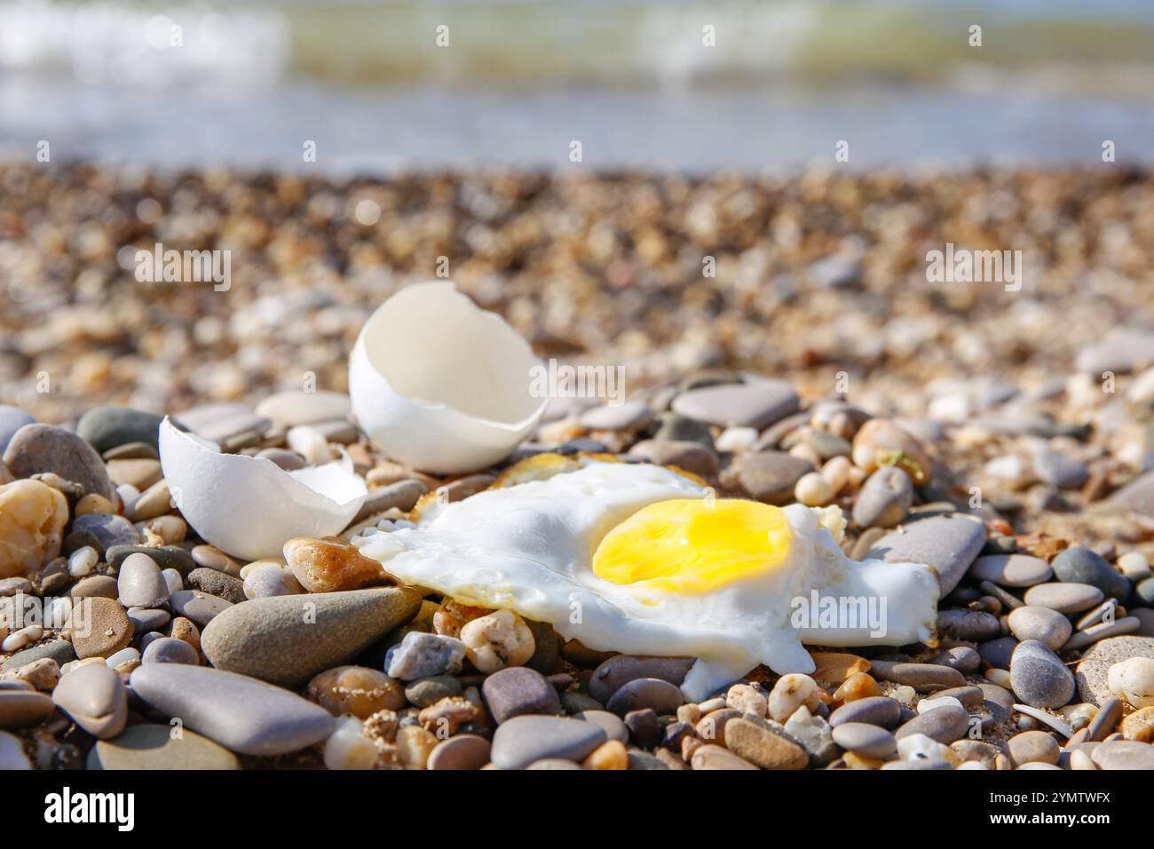 Ein Hühnerei wurde im Sand gebraten. Heißes Wetter am Strand. Stockfoto