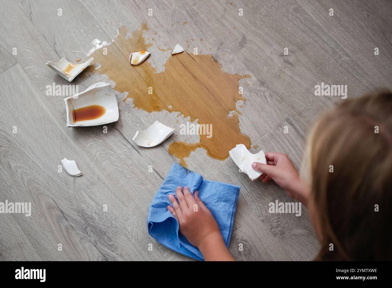 Eine kaputte Tasse Kaffee fiel auf Laminat, Kaffee verschüttete auf dem Boden. Stockfoto