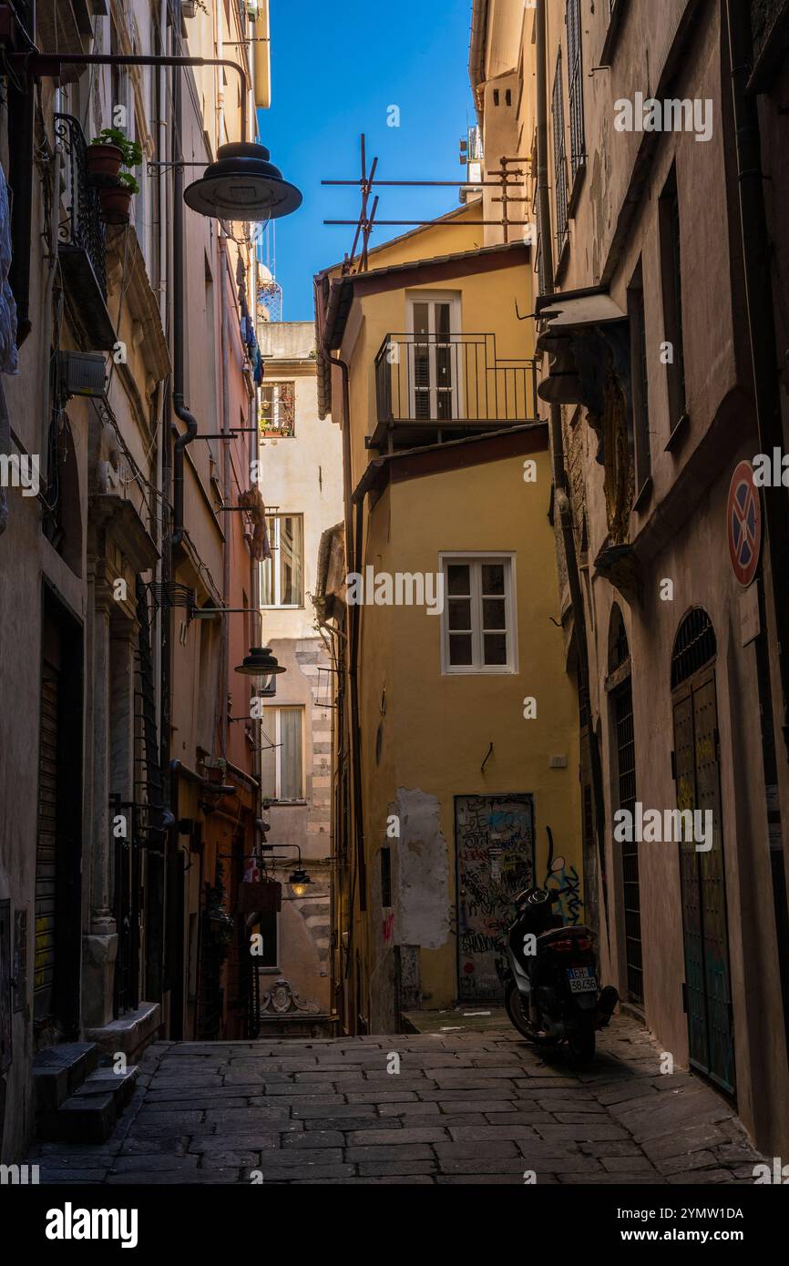 Blick auf die alte alte alte schmale Straße bergab mit farbenfrohen Fassaden an Häusern, die zum Hafen von Genua, Genua, Ligurien, Italien 09.01.2024 führt Stockfoto