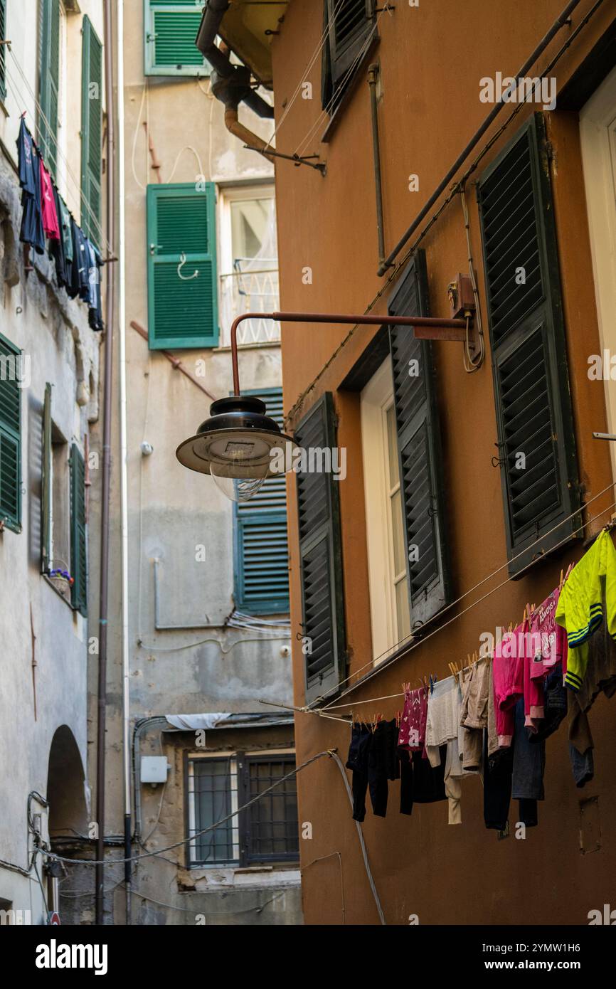 Blick auf die alte alte alte schmale Straße bergab mit farbenfrohen Fassaden an Häusern, die zum Hafen von Genua, Genua, Ligurien, Italien 09.01.2024 führt Stockfoto