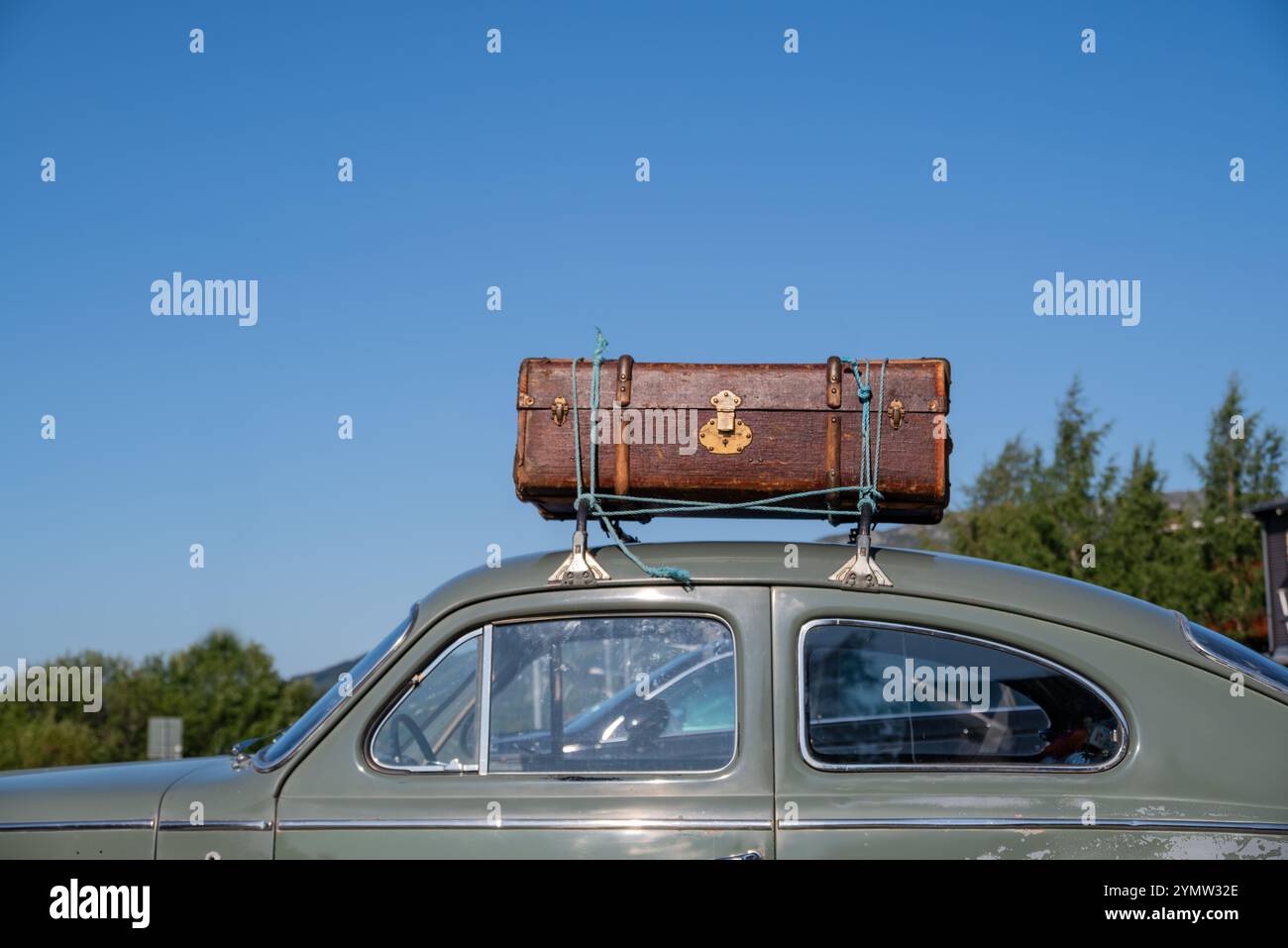 Alter Koffer auf dem Dach eines Autos statt einer modernen Dachbox. Stockfoto