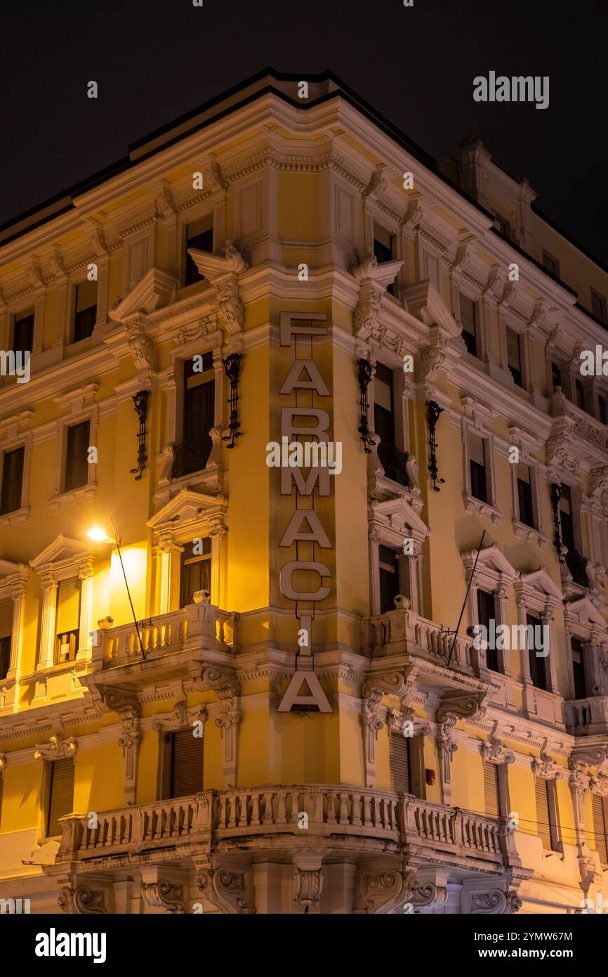 Dekoriertes Schild einer antiken Apotheke in einem hohen Gebäude an der Ecke eines Platzes (La Farmacia di Piazza Goldoni) im historischen Zentrum von Triest Stockfoto