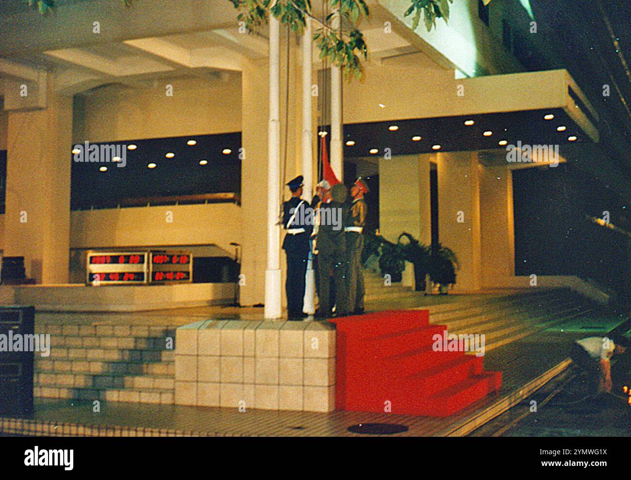 Die Farbparty der People's Liberation Army (PLA) bereitet sich darauf vor, die chinesische Flagge in der Prince of Wales Kaserne in Hongkong um genau 23:00 Uhr am 30. Juni 1997 zu hissen, wie auf der digitalen Countdown-Uhr dahinter angegeben (undeutlich) Stockfoto