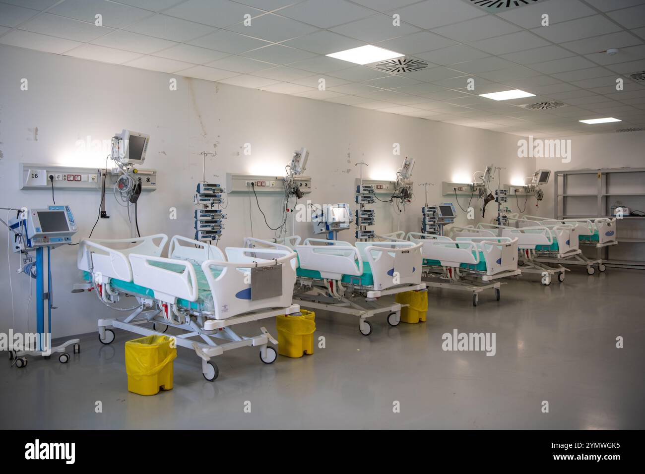 Moderne Technik in leerem Intensivraum mit verschiedenen Geräten, Betten und Kissen. Stockfoto