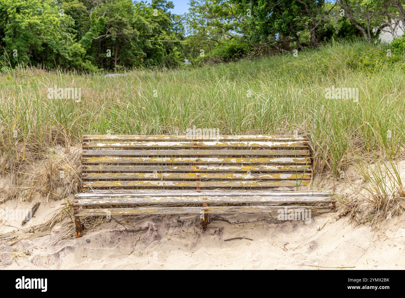 Alte verwitterte Bank teilweise mit Sand am Strand begraben Stockfoto