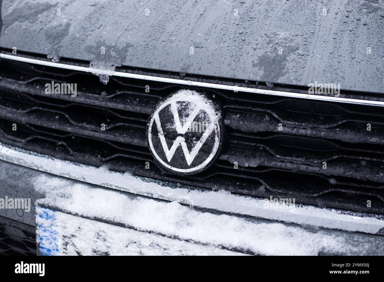 Nahaufnahme eines von Frost und Schnee überzogenen Volkswagen-Logos, das die Winterbedingungen und das Markenzeichen für Fahrzeuge hervorhebt. Stockfoto